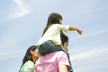 娘を肩車する父親とそばに立つ母親の後姿