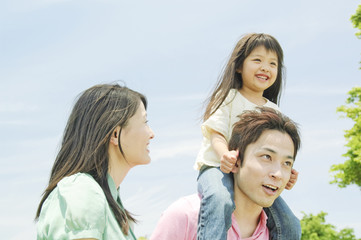 娘を肩車する父親とそばに立つ母親