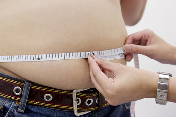 肥満男性の腹周りを測る女性の手元