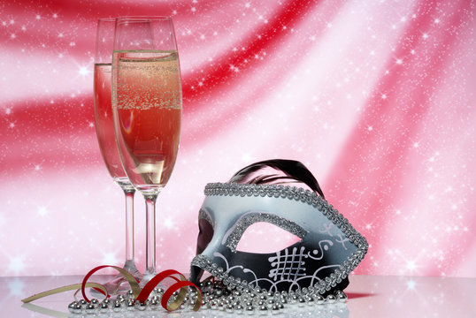 Glasses with champagne and venetian mask on an abstract backgrou