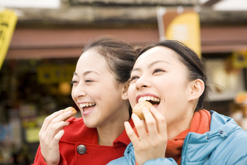 観光地でまんじゅうを食べる女性2人