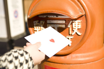 ポストに手紙を投函する女性の手元