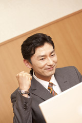 パソコンを見ながらガッツポーズをするビジネスマン