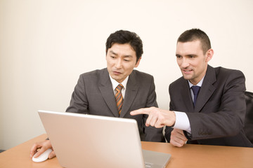 パソコンを見る日本人ビジネスマンとアメリカ人ビジネスマン