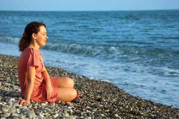 Fototapeta na wymiar young woman sits ashore of sea