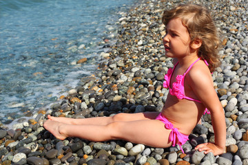 little girl sits on beach