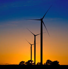 Wind turbines silhouettes over blue and orange sky; sunset