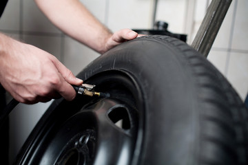 Mechanic filling air into a car tyre.