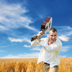 man smashing guitar blue sky