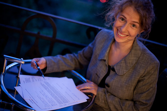 junge Frau im Business sieht sich einen Vertrag an, lächelt