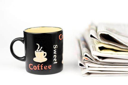 Coffee cup and stack of newspapers