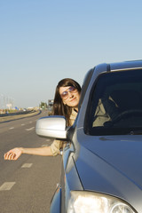 Happy young brunette driving silver car