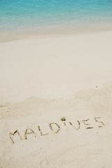 Maldives written in a sandy tropical beach