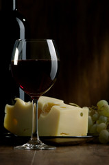 Glass of wine and cheese on a dark background