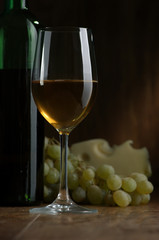 Glass of wine and cheese on a dark background