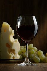 Glass of wine and cheese on a dark background