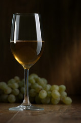 Glass of wine and grapes on a dark background