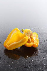 Paprika, gelb, halbiert, auf schwarzem  Acryl