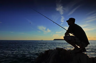 Foto auf Acrylglas Angeln Mann fischt bei Sonnenuntergang