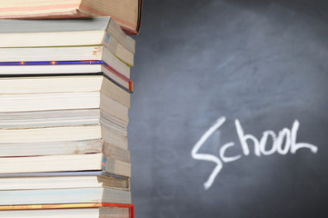 Stack of books in front of a chalkboard.