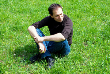 Naklejka na ściany i meble young man sitting on the grass
