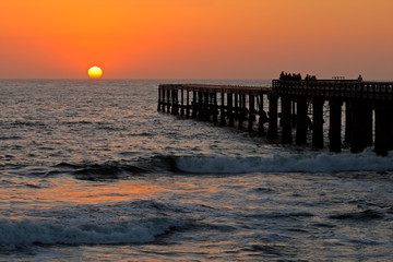 Fototapeta premium Silhouetted coastal pier with a glowing sunset