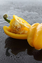Paprika, gelb, halbiert, auf schwarzem  Acryl
