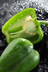 Paprika, gruen, halbiert, auf schwarzem  Acryl