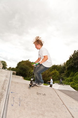 Kinder fahren Roller im Skate Park und üben Tricks
