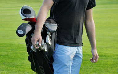 Male golfer carrying clubs, close-up