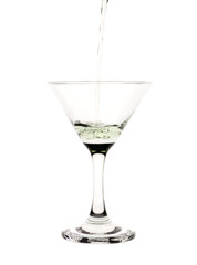 Green liquid pouring into a martini glass.