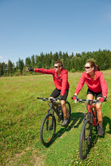 Fototapeta na wymiar Sportive couple riding mountain bike in meadow