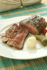 grilled pepper steak with some sour vegetables on a white plate