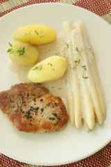 pork chop with potato and asparagus on a plate