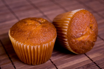 Two muffins on bamboo mat.