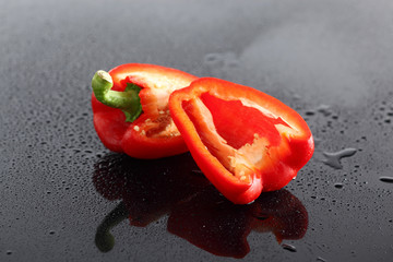 Paprika, rot, halbiert, auf schwarzem  Acryl