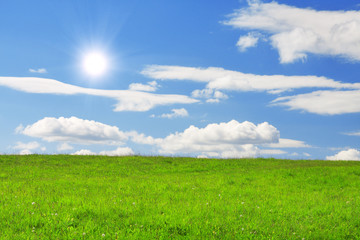 Obraz premium Green hill under blue cloudy sky whit sun