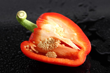 Paprika,rot, halbiert, auf schwarzem  Acryl