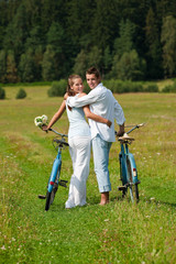 Romantic couple walking with old bike in meadow
