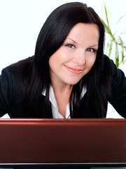 smiling brunette businesswoman in office with laptop