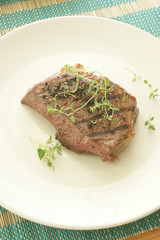 grilled pepper steak with organic herbs on a plate