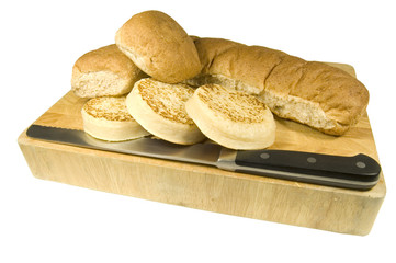 bread board with knife, muffins, roll and baps isolated on white