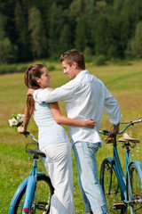 Fototapeta na wymiar Romantic couple walking with old bike in meadow
