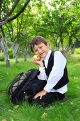 schoolboy with backpack and apple outdoors