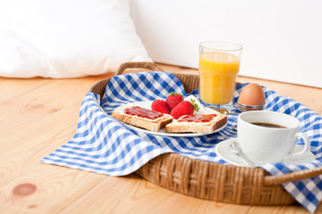 Homemade breakfast on wicker tray with checked teacloth
