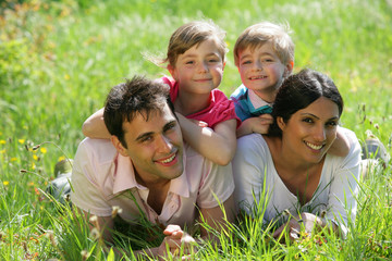 Fototapeta premium Para z dziećmi, leżąc na trawie