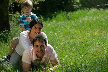Naklejka na ściany i meble homme et femme avec un petit garçon couchés dans l'herbe