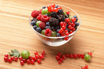 Fruit mix in the glass container, on a table from straw