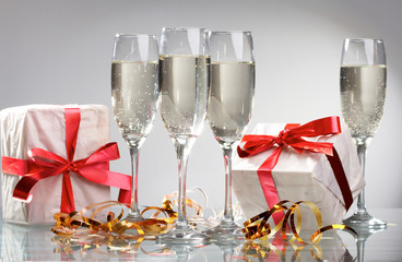 Glasses of champagne, gifts with red tapes and bows