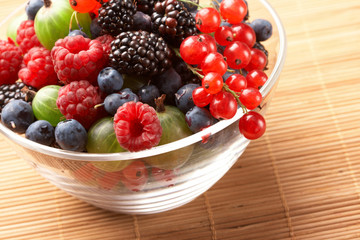 Fruit mix in the glass container, on a table from straw